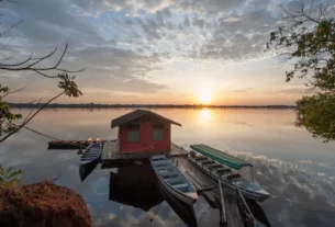 Pousada de pesca esportiva às margens de rio brasileiro com barcos e estrutura para pescadores.