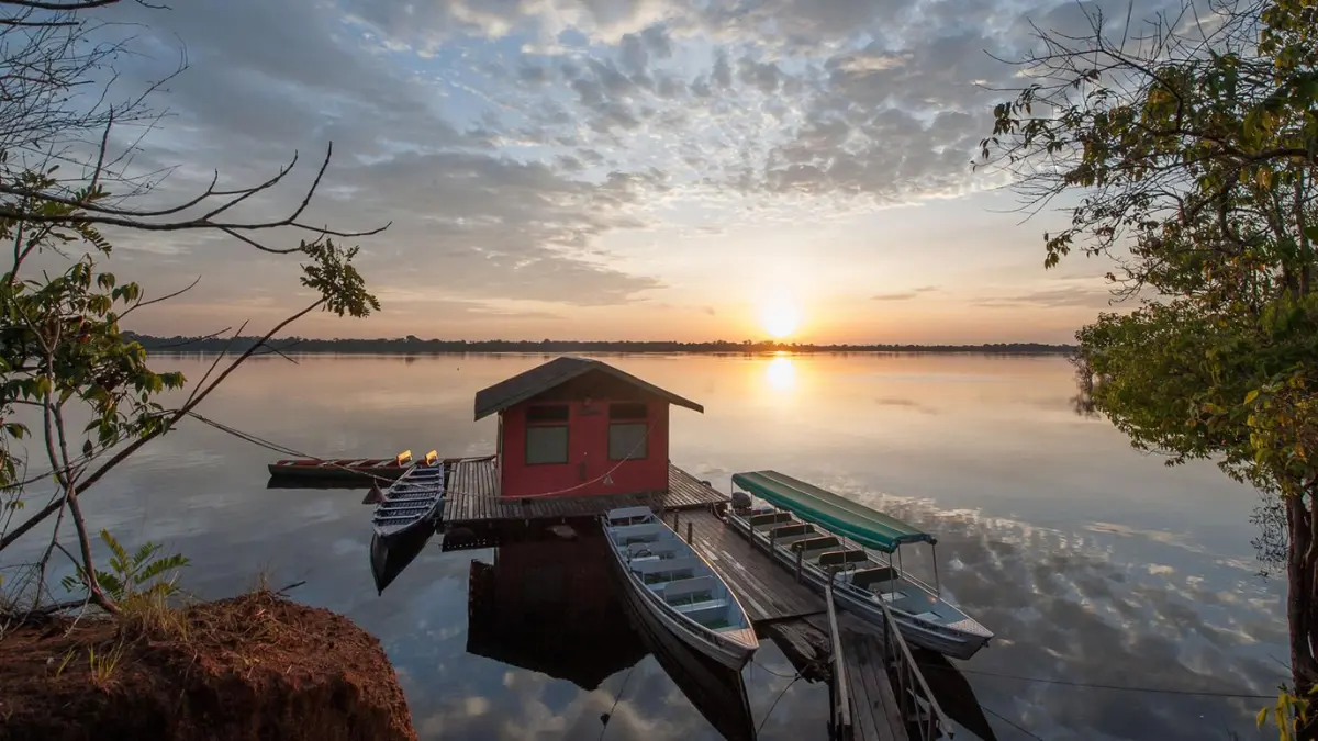 Pousada de pesca esportiva às margens de rio brasileiro com barcos e estrutura para pescadores.