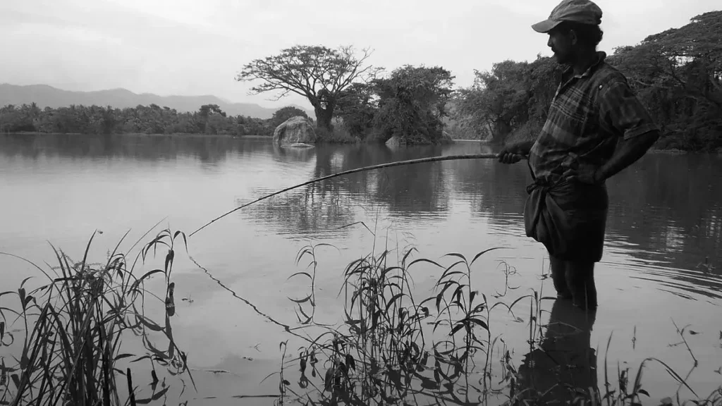 Pescador observando rio e estruturas naturais antes de iniciar a pescaria.