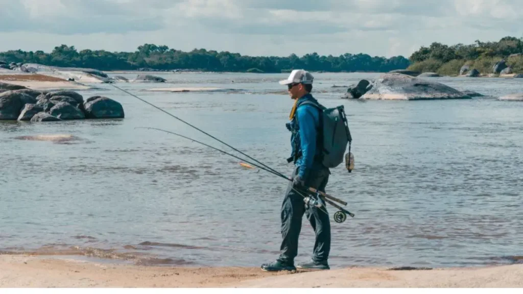Pescador observando correntezas, remansos e estruturas naturais para identificar pontos produtivos em um rio.