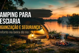 Camping para pescaria montado na beira do rio ao entardecer, com barraca iluminada, vara de pesca, caixa térmica e fogueira acesa.