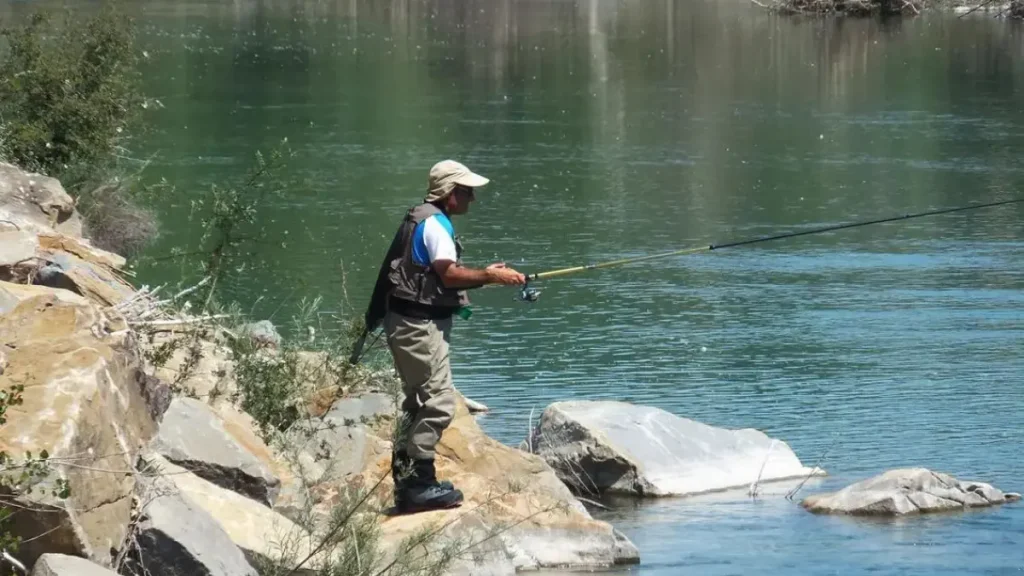 Pescador analisando estruturas e correnteza para localizar peixes predadores.