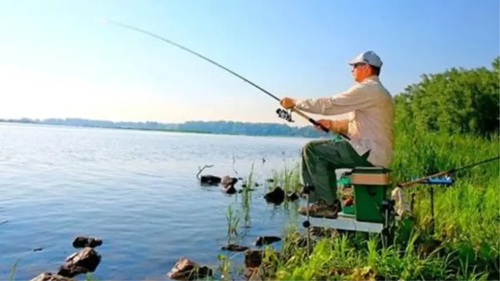 Pescador de margem usando vara longa para alcançar pontos distantes.